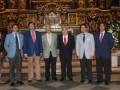 Grupo de hombres en trajes posando frente a un altar dorado en una iglesia.