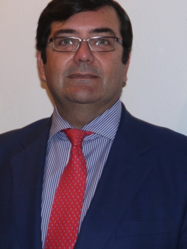 Retrato de hombre con traje azul y corbata roja, frente a fondo blanco.