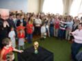 Un grupo de personas en una sala de conferencias, con un niño en el centro sosteniendo la Copa del Mundo. La imagen muestra a varios espectadores y fotógrafos capturando el momento.