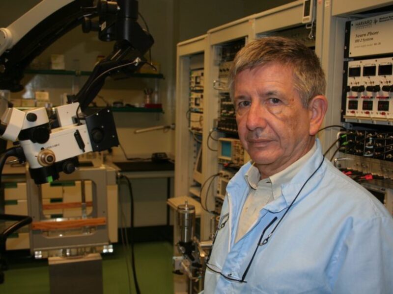 Investigador en laboratorio con equipo de microscopio y sistemas de control de precisión.