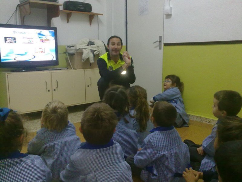 Maestro explicando a un grupo de niños sentados en círculo en una aula.