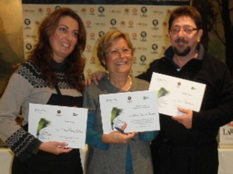 Tres personas sonrientes sosteniendo diplomas en una conferencia o evento.