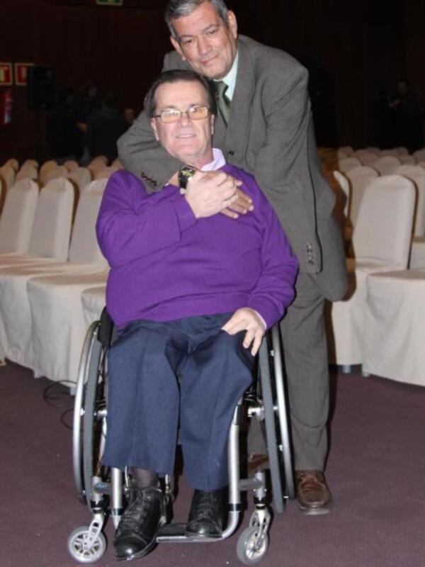 Un hombre en silla de ruedas con un amigo en un evento formal.