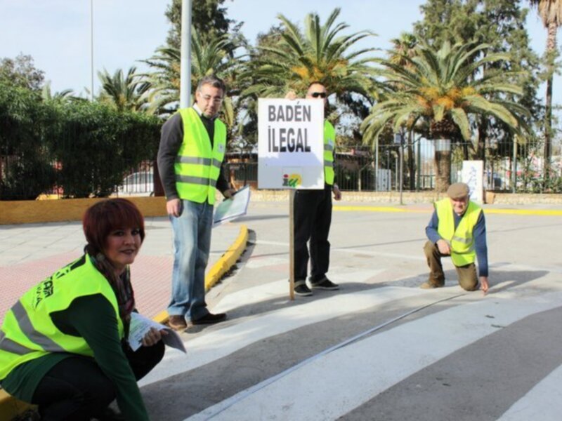 Personas con chalecos amarillos señalando "Badén Illegal" en una carretera.