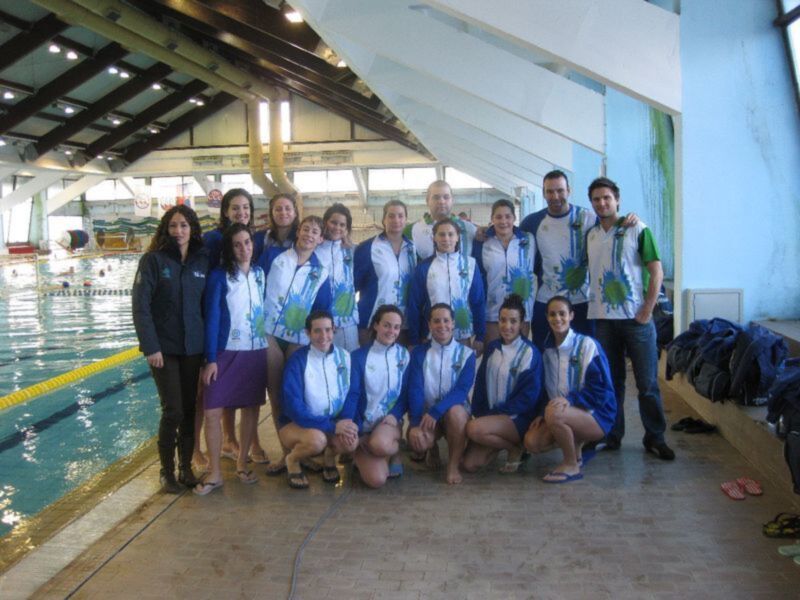 Equipo de natación posando junto a la piscina en un centro acuático.