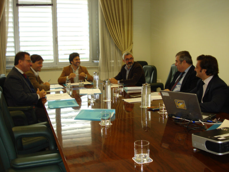 Reunión de negocios en una sala de conferencias con un grupo de hombres en trajes discutiendo alrededor de una mesa.