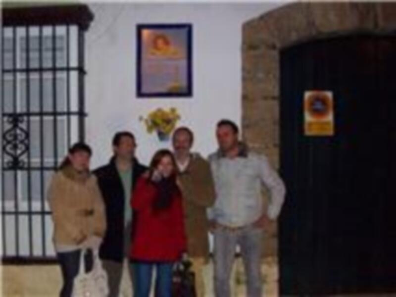 Una familia posando frente a una casa con una bandera en el marco.