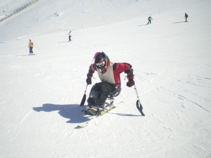 Un esquiador adaptado disfruta de la nieve en una pista de esquí.