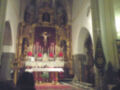 Interior de una iglesia con altar central, vitrales y personajes en el fondo.