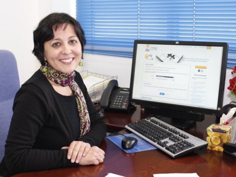 Profesional sonriente en su escritorio, mostrando un sistema de gestión de recursos humanos en la pantalla del ordenador.