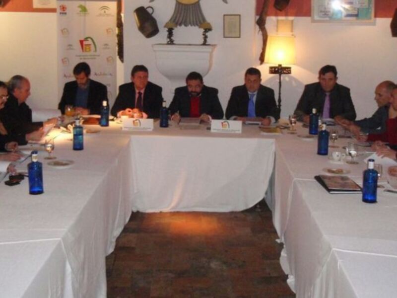 Reunión de negocios en una sala elegante con participantes sentados alrededor de una mesa larga.