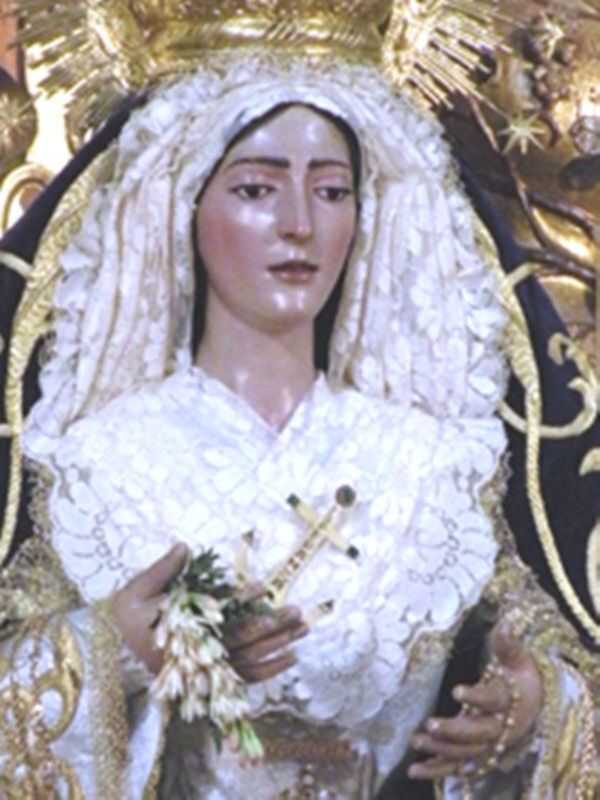 Retrato de una figura religiosa vestida con una capa blanca y un tocado dorado, sosteniendo una cruz y flores en sus manos.
