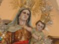 Estatua de la Virgen con el Niño Jesús, adornada con una corona dorada y vestimentas ricamente bordadas.
