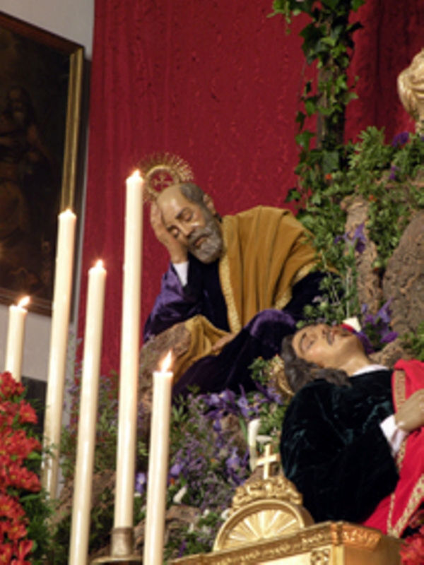 Representación religiosa de la Pasión de Cristo, con figuras en trajes tradicionales y velas iluminando el altar.