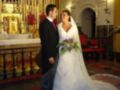 Boda en iglesia con novia y novio, vestidos de gala, flores en el altar.