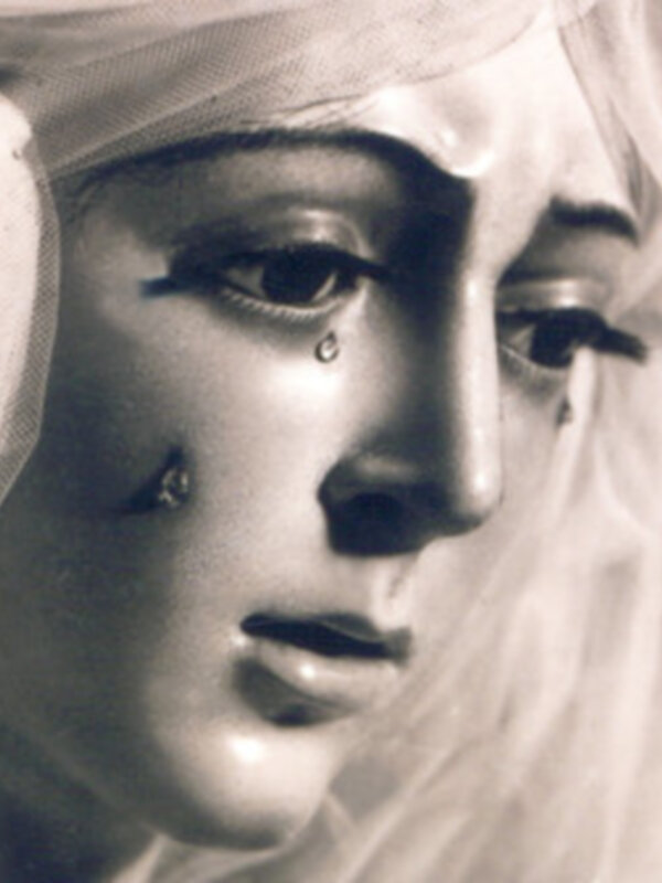 Una imagen en blanco y negro de una estatua de una mujer con una expresión triste, llorando una lágrima.