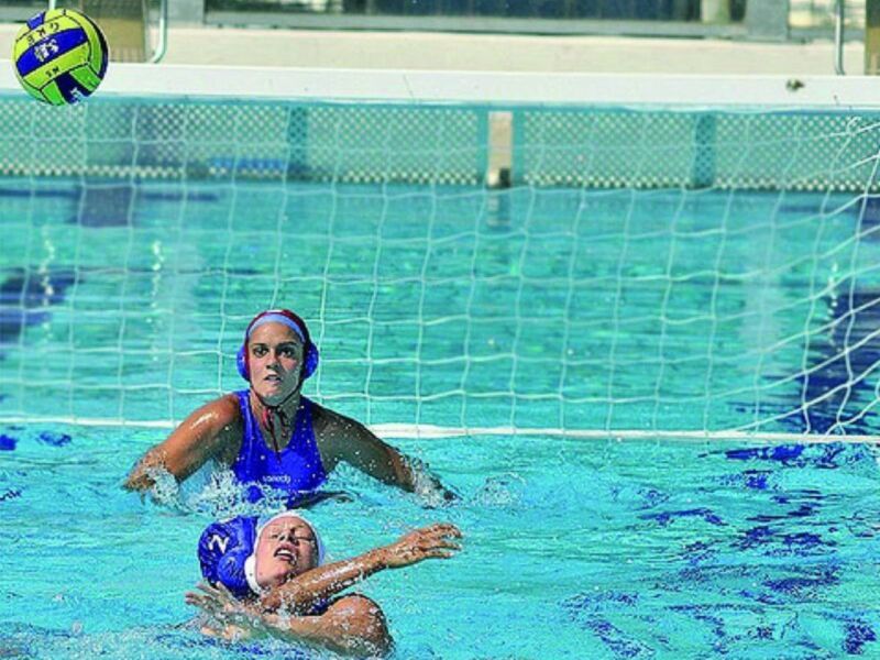 Jugadora de waterpolo en acción durante un partido en la piscina.