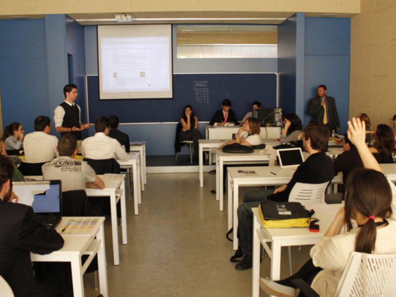 Clase universitaria en un aula moderna con estudiantes participando activamente en el aprendizaje.
