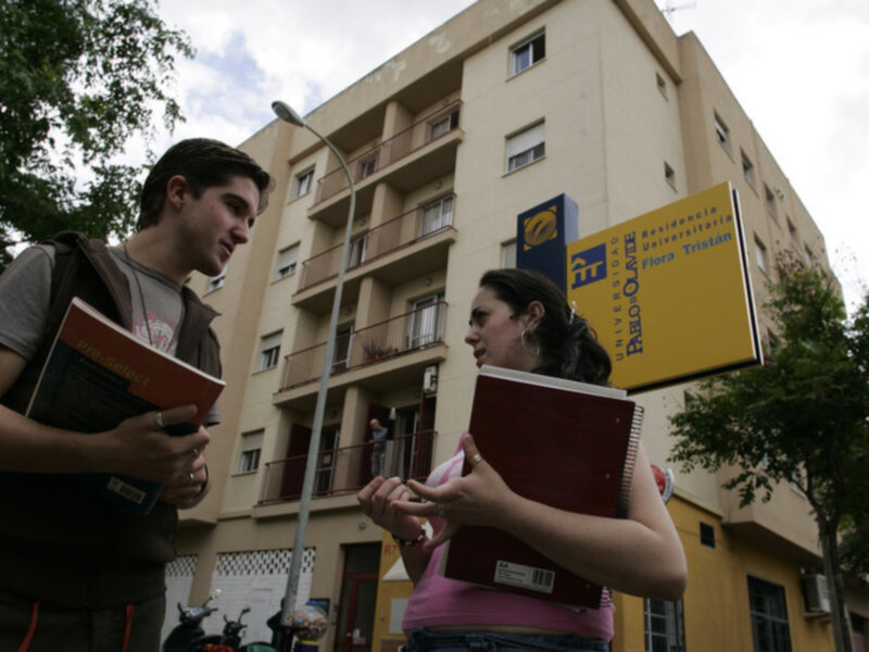 Estudiantes conversando frente a la residencia universitaria Flora Tristan en un día soleado.