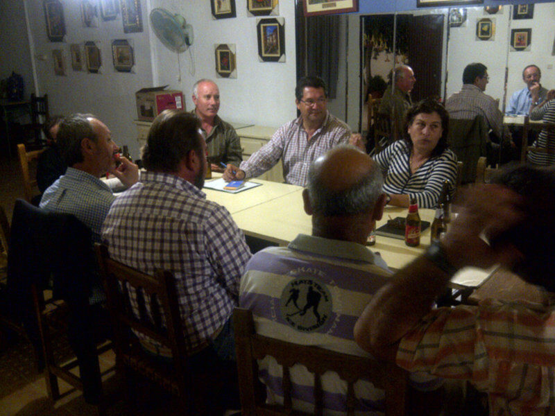 Reunión de adultos en una mesa de café, discutiendo y bebiendo.