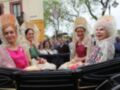 Desfile de carrozas tradicionales durante una feria, mujeres vestidas con trajes típicos andaluces.