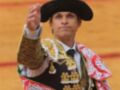 Un torero en traje tradicional español, con un sombrero de copa y un chaleco decorado.