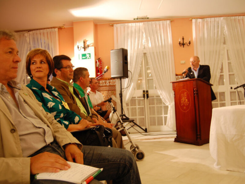 Conferencia en sala con público escuchando a un orador en el podio.