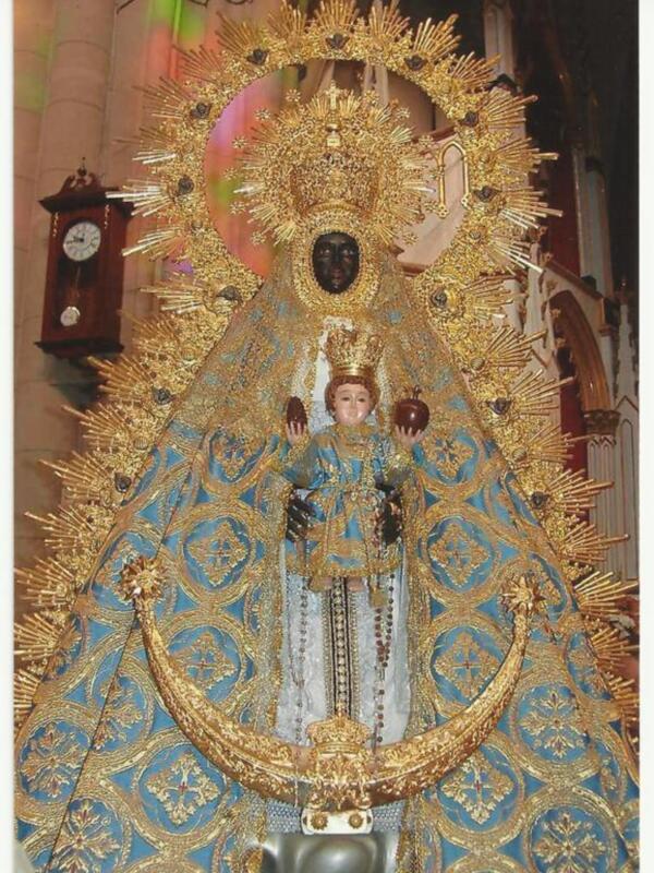 Imagen de la Virgen del Carmen con ornamentos dorados y vestimenta azul en un entorno eclesiástico.