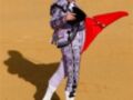 Un torero en traje tradicional con banderillas, posando sobre un fondo de arena.