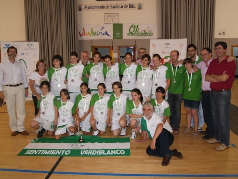 Equipo deportivo con medallas y trofeo en una ceremonia de premiación en Sanlúcar de Barrameda.