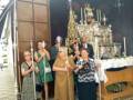 Una procesión religiosa con personas vestidas formalmente, sosteniendo palos y una figura en un altar.