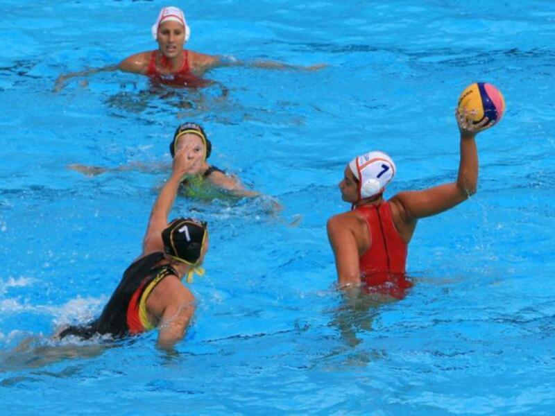 Jugadoras de waterpolo en acción durante un partido en una piscina.