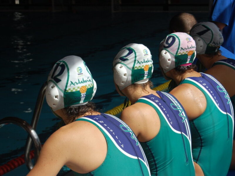 Jugadoras de waterpolo en el borde de la piscina, listas para el juego.