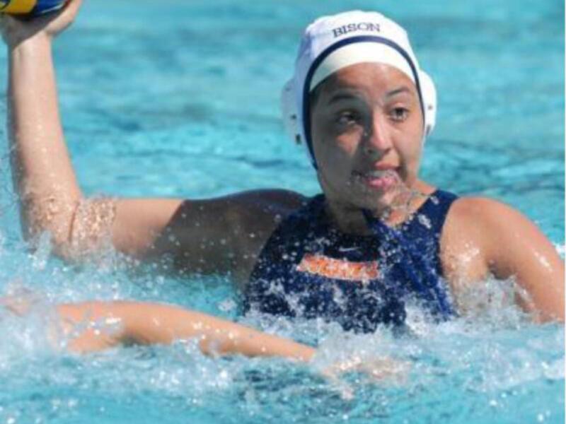 Jugadora de waterpolo en acción, sosteniendo el balón en una piscina.