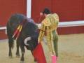 Un torero con traje tradicional se enfrenta a un toro en una plaza de toros.