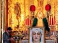 Interior de una iglesia con altares dorados y estatuas religiosas. En el centro, una imagen de la Virgen María con un niño en sus brazos. A su lado, una estatua de la Virgen María con un niño en sus manos. En el fondo, un altar dorado con velas y adornos. Una persona habla en una tribuna de madera, frente a un grupo de personas que observan la imagen.