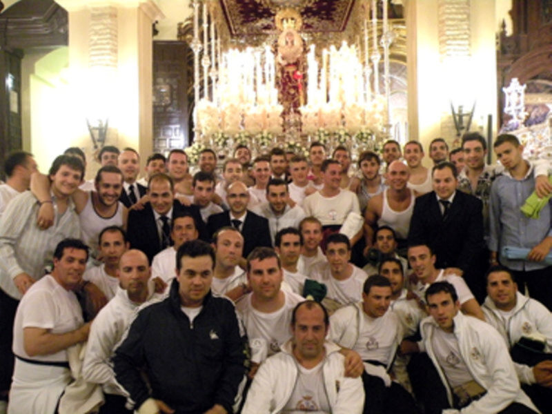 Grupo de personas posando en una iglesia con una imagen religiosa en el fondo.