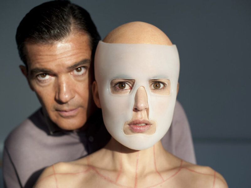Un hombre y una persona con una máscara facial en un entorno oscuro.