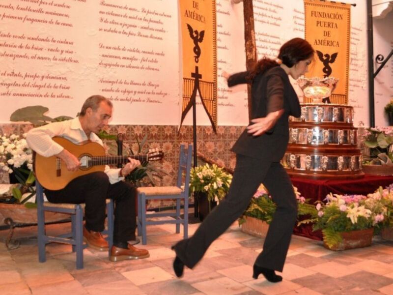 Danza flamenca con música en vivo en un escenario decorado con banderines y flores.