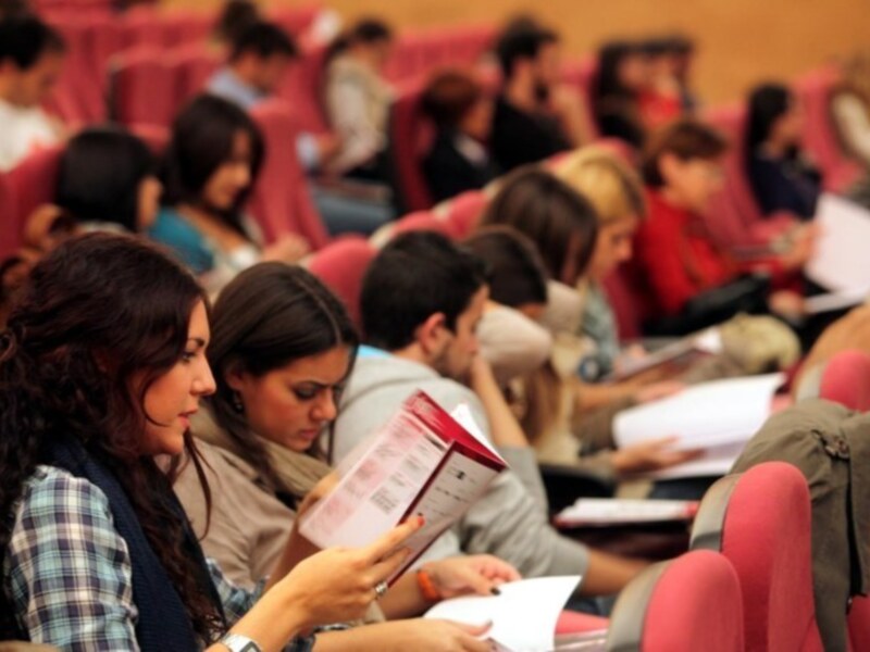 Estudiantes en una sala de conferencias, concentrados en sus documentos de estudio.