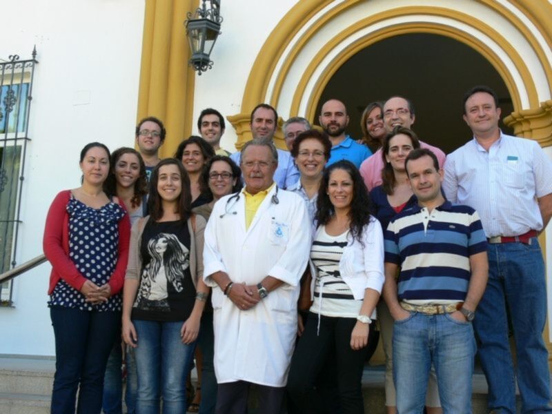 Grupo de personas posando frente a una estructura con arcos amarillos y una puerta de hierro.