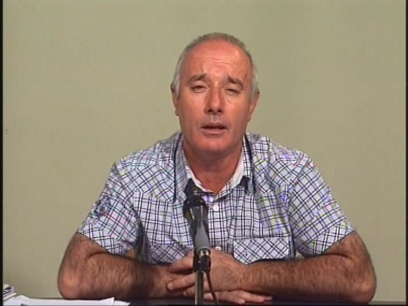 Hombre hablando en una conferencia o reunión con un micrófono en frente.