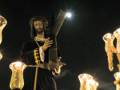 Procesión nocturna con imágenes religiosas iluminadas por faroles y velas.