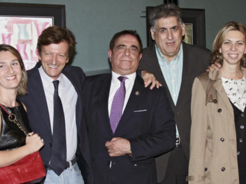Grupo de personas en trajes y abrigos posando juntos en un evento formal.