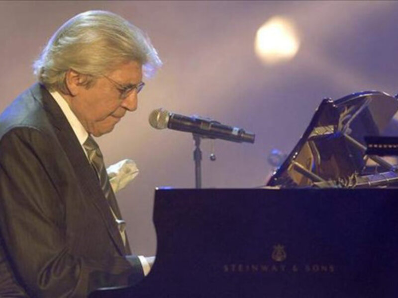 Artista tocando el piano Steinway & Sons en un escenario con iluminación dramática.