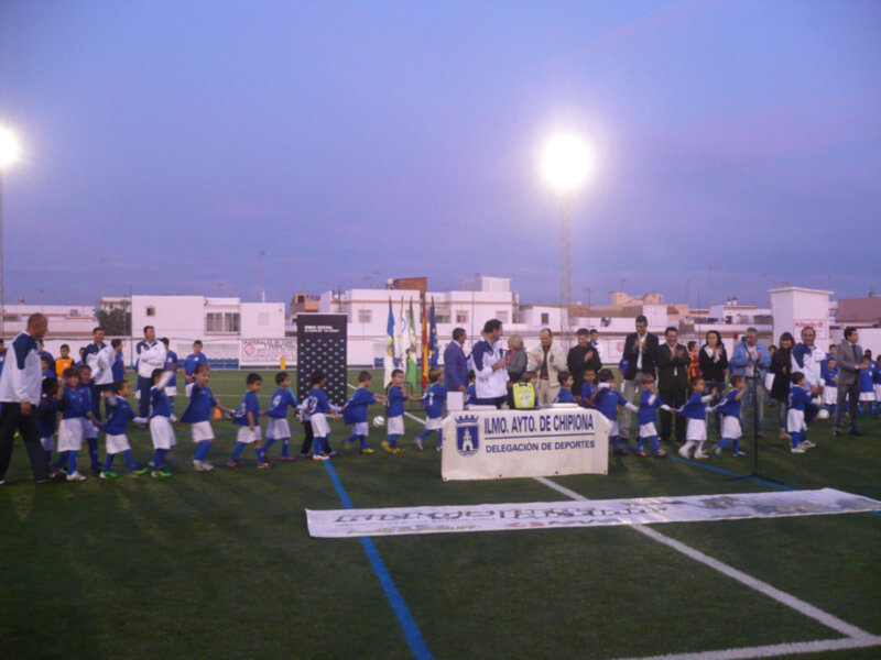 Jóvenes jugadores de fútbol en un campo de fútbol durante un evento deportivo en Chipiona, España.