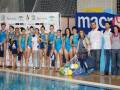 Equipo femenino de natación posando frente a la piscina.