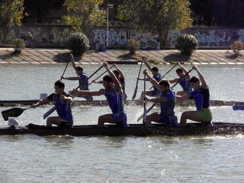 Equipo de remo en competencia, trabajando juntos en un barco de remo en un canal urbano.