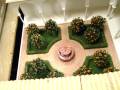 Miniatura de un jardín con árboles frutales y una fuente central en un entorno de madera.