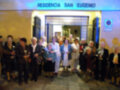 Una agrupación de personas posando frente a la Residencia San Eugenio, con una puerta abierta y una placa de identificación en el fondo.